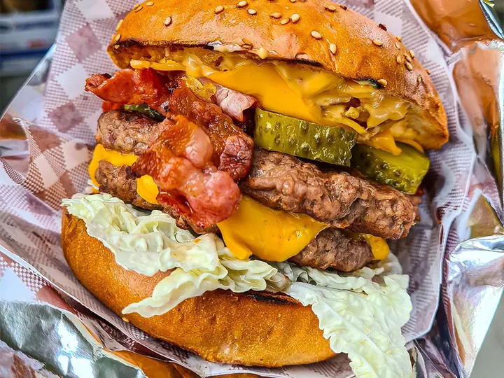 A double burger with bacon and cheddar wrapped in foil